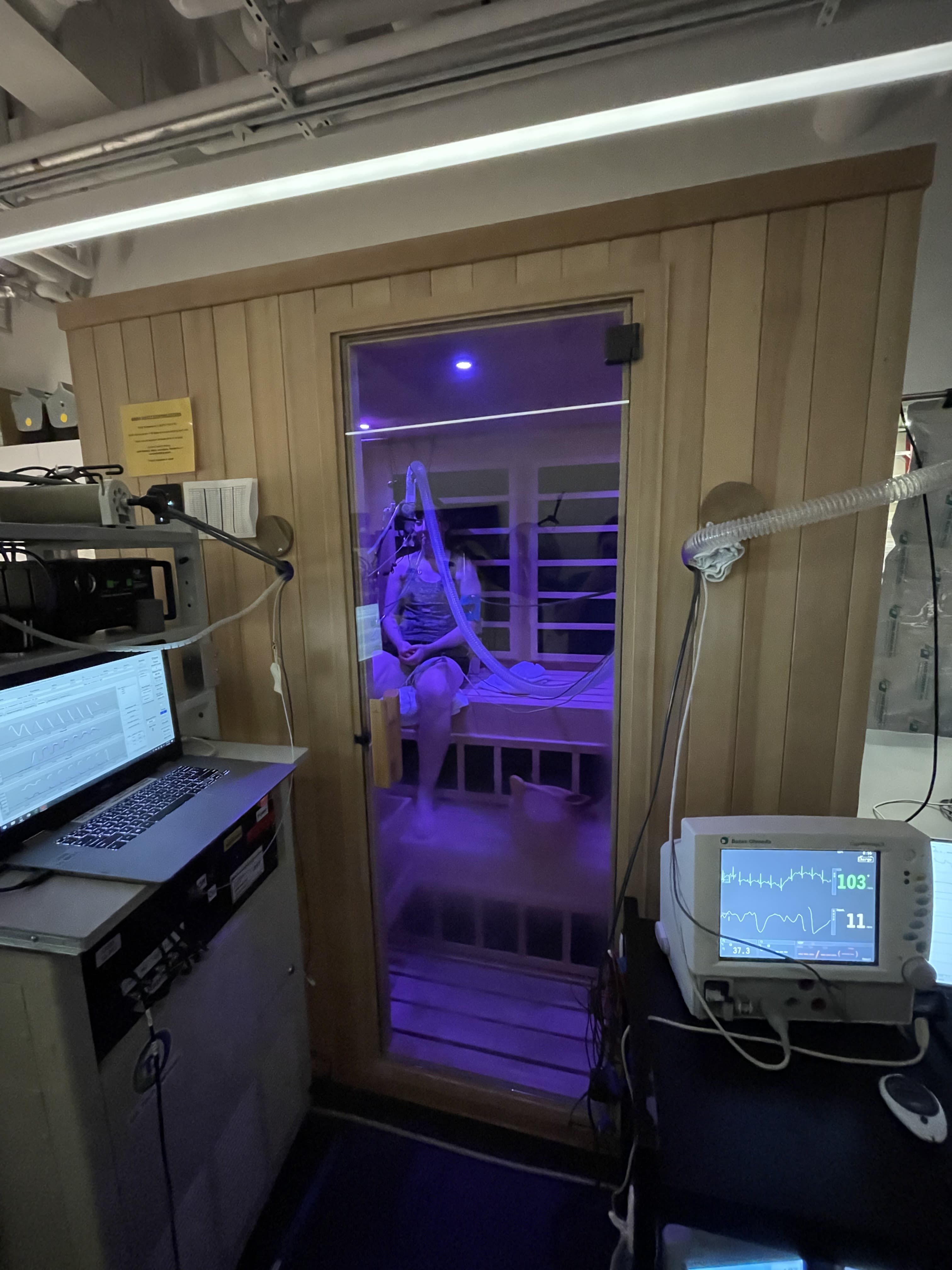 A person wearing a towel sits in a sauna in a laboratory setting