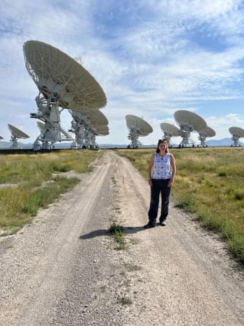 Cendes standing in front of a group of radio telescope dishes