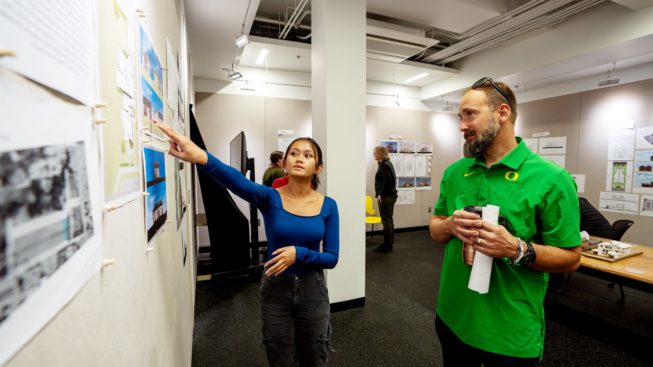 Student pointing to drawings on studio wall
