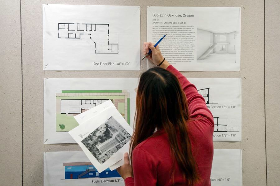 Student working on architectural drawings posted on wall