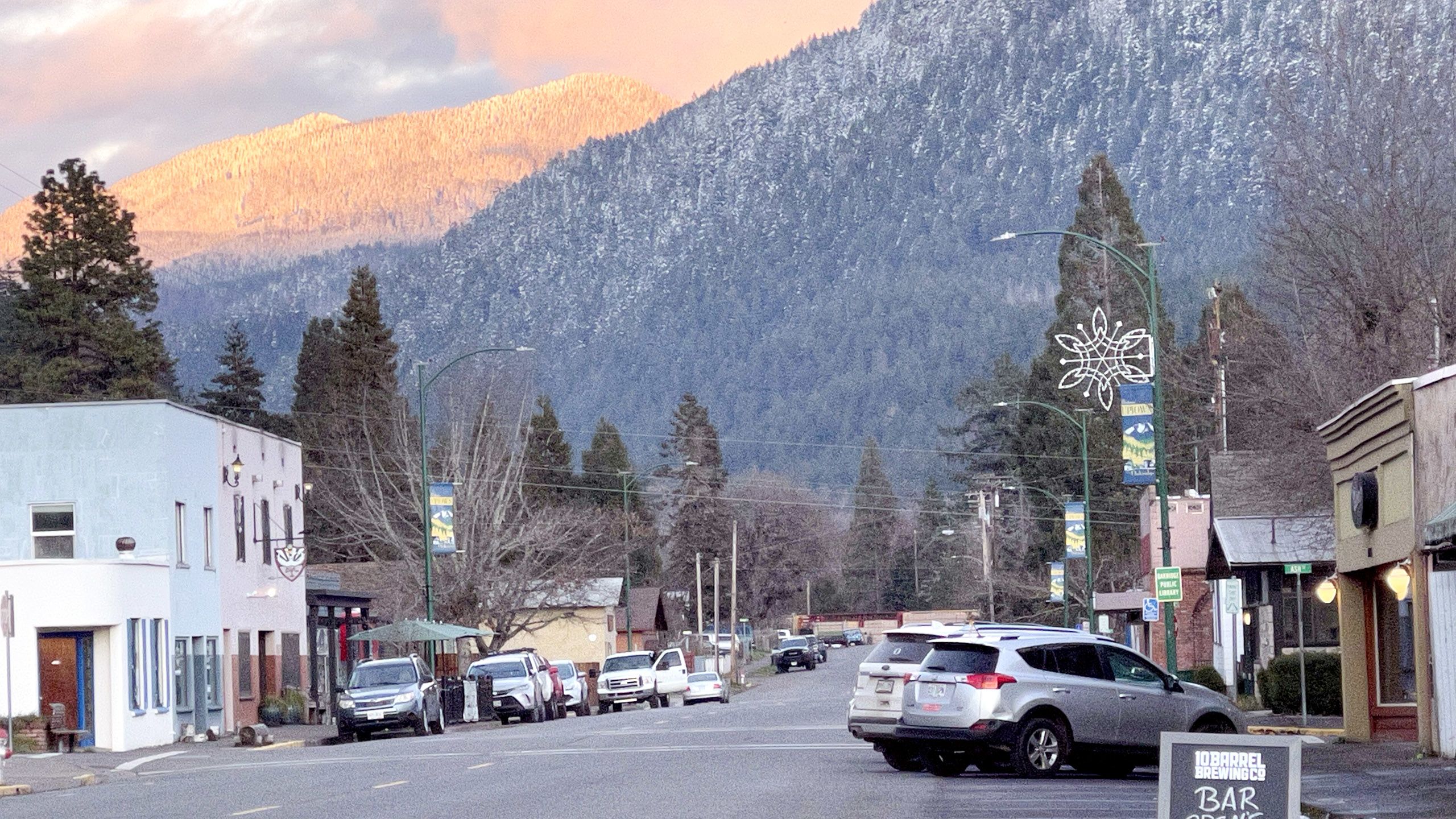 Small town streets with cars and snowy hill in background