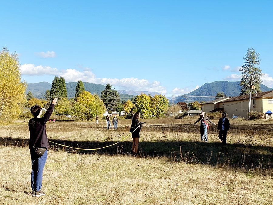 Students use tape measure in open field near houses