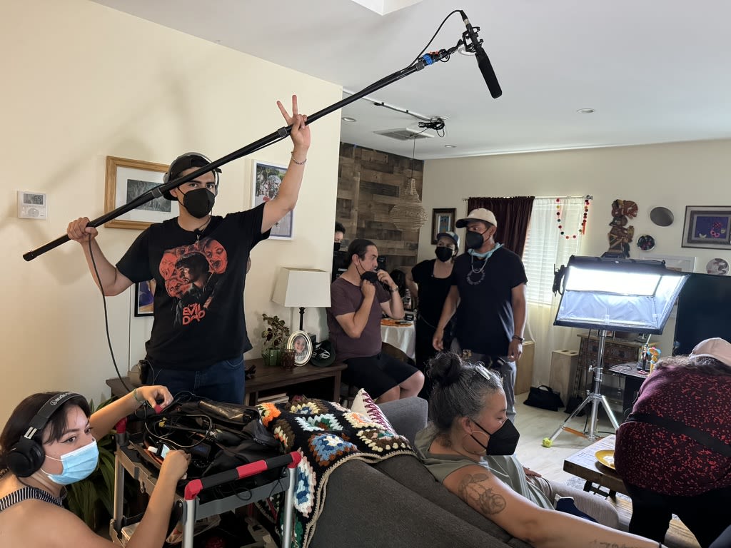 a person holding a boom microphone on a film set in a house