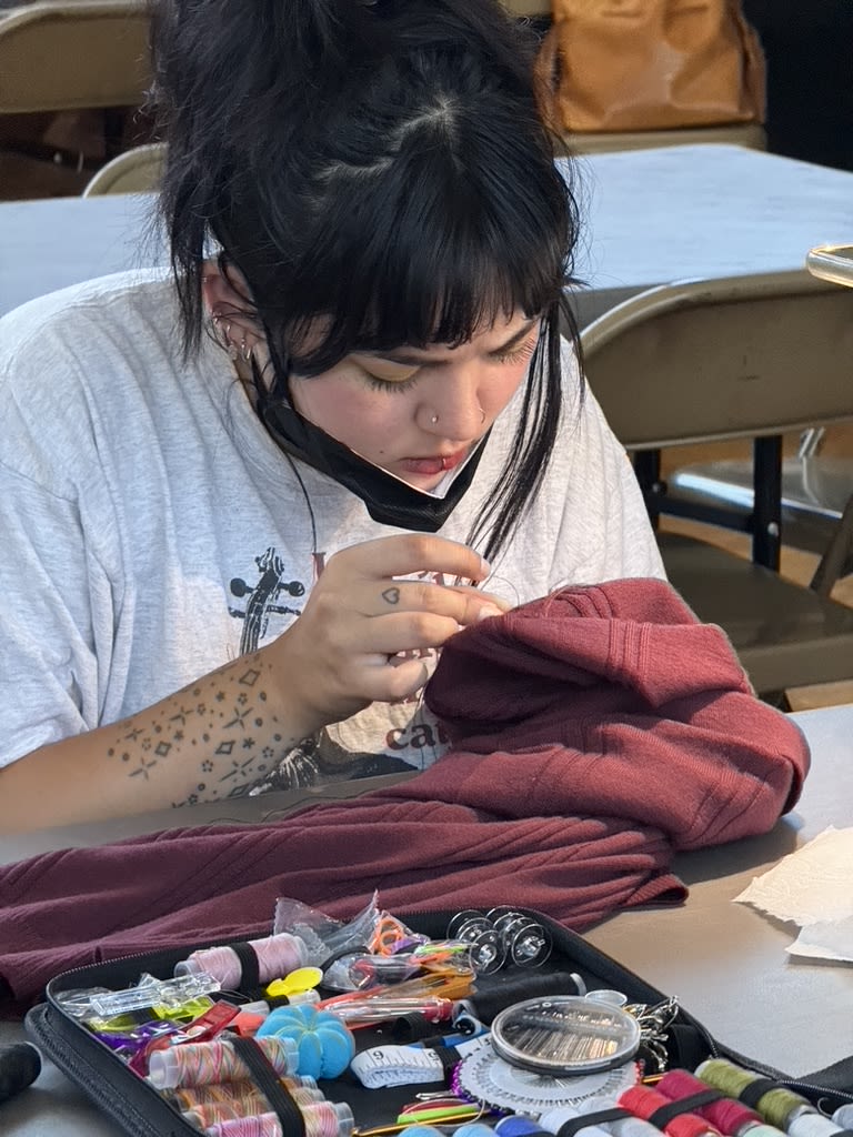 a person with dark hair mends a t-shirt