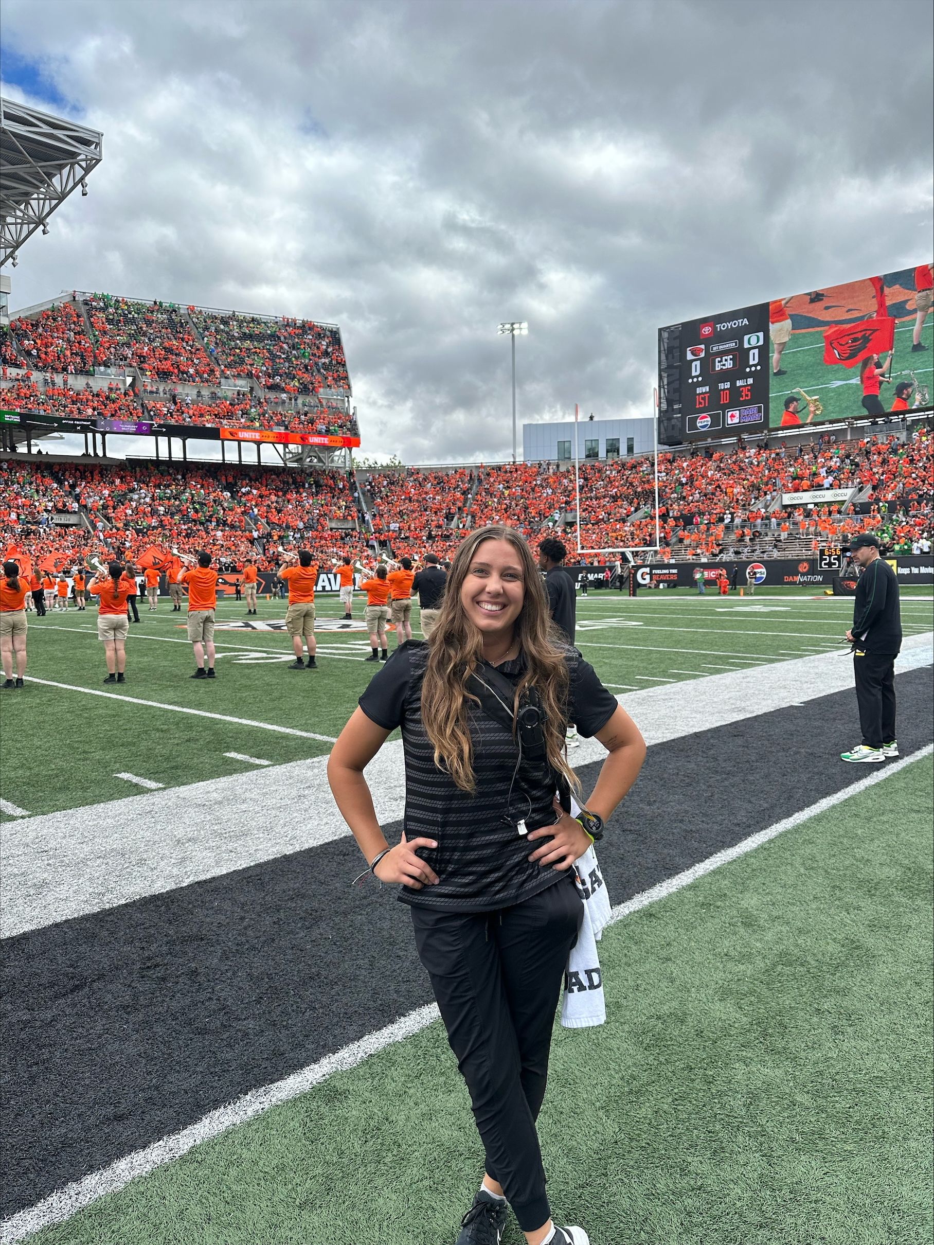 a woman stands on the sideline at Oregon State University's football field. 
