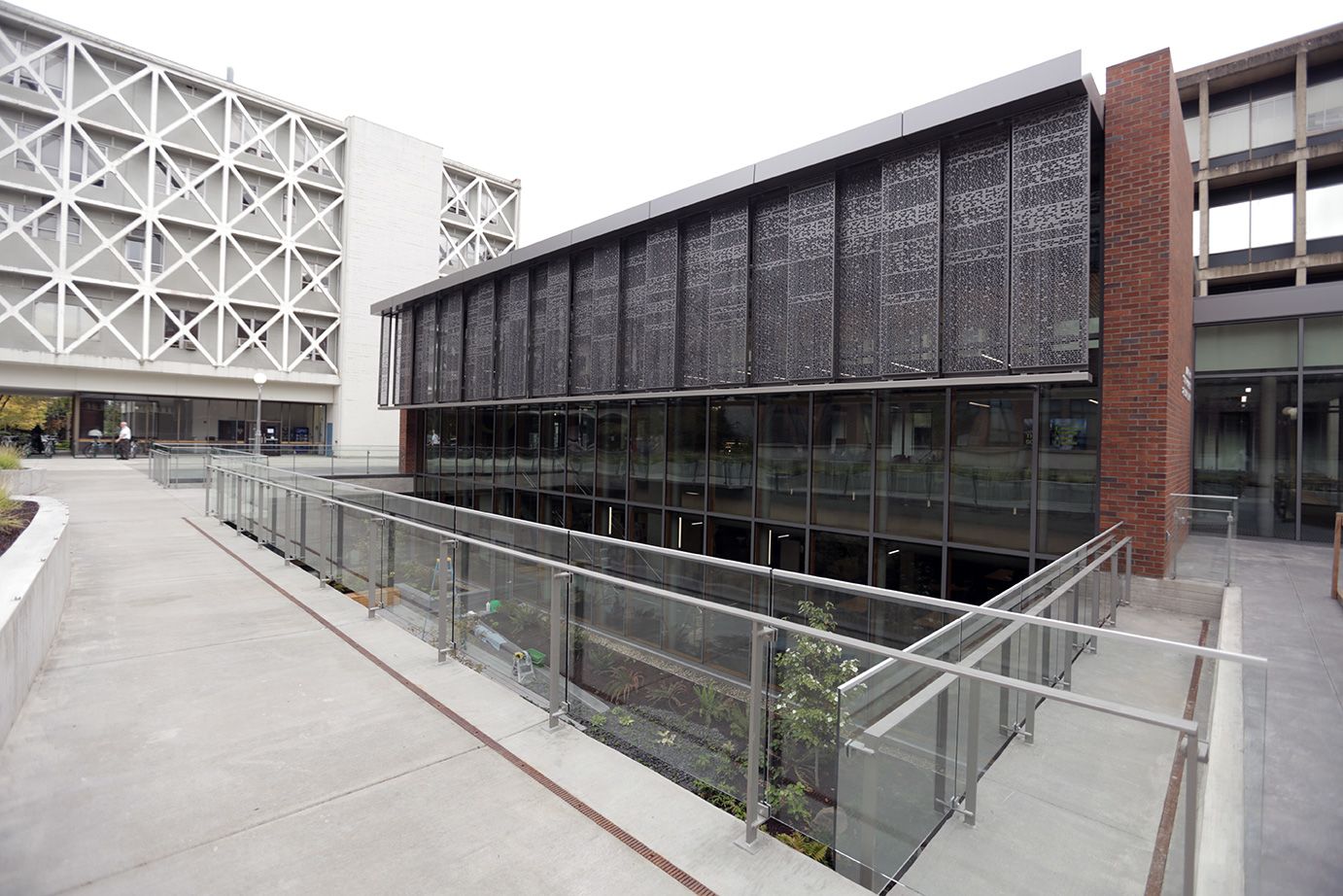 A modern building exterior with glass and decorative metal panels with lines, blocks, and holes that represent the zebrafish genetic code..