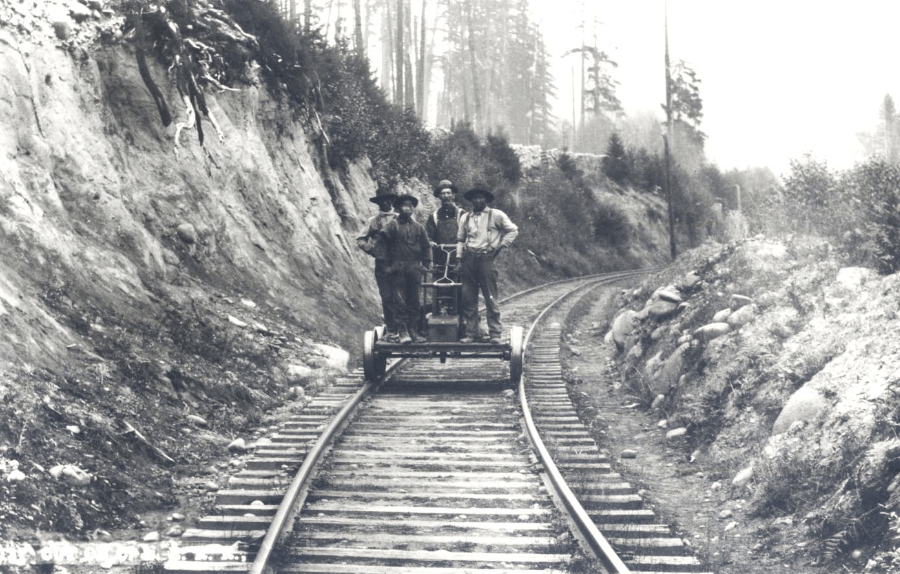 a black and white archival photo of four men working on a railroad from the 1930s
