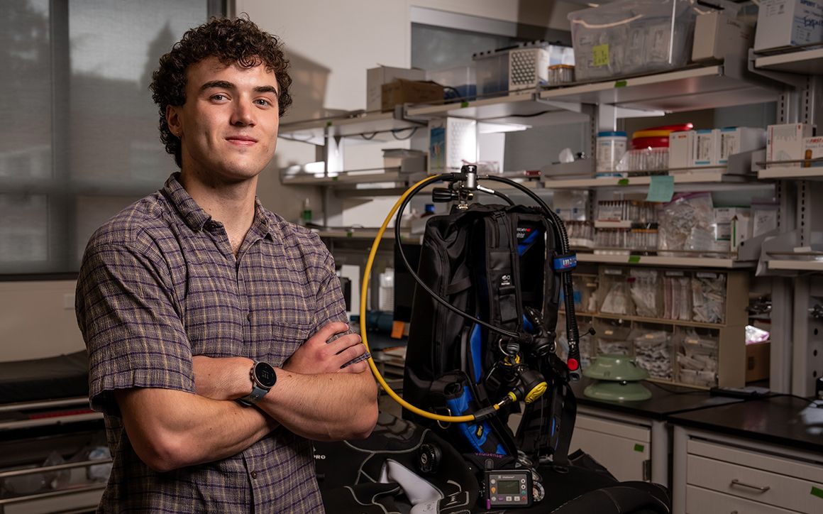 Tucker Orman poses in the lab with SCUBA gear