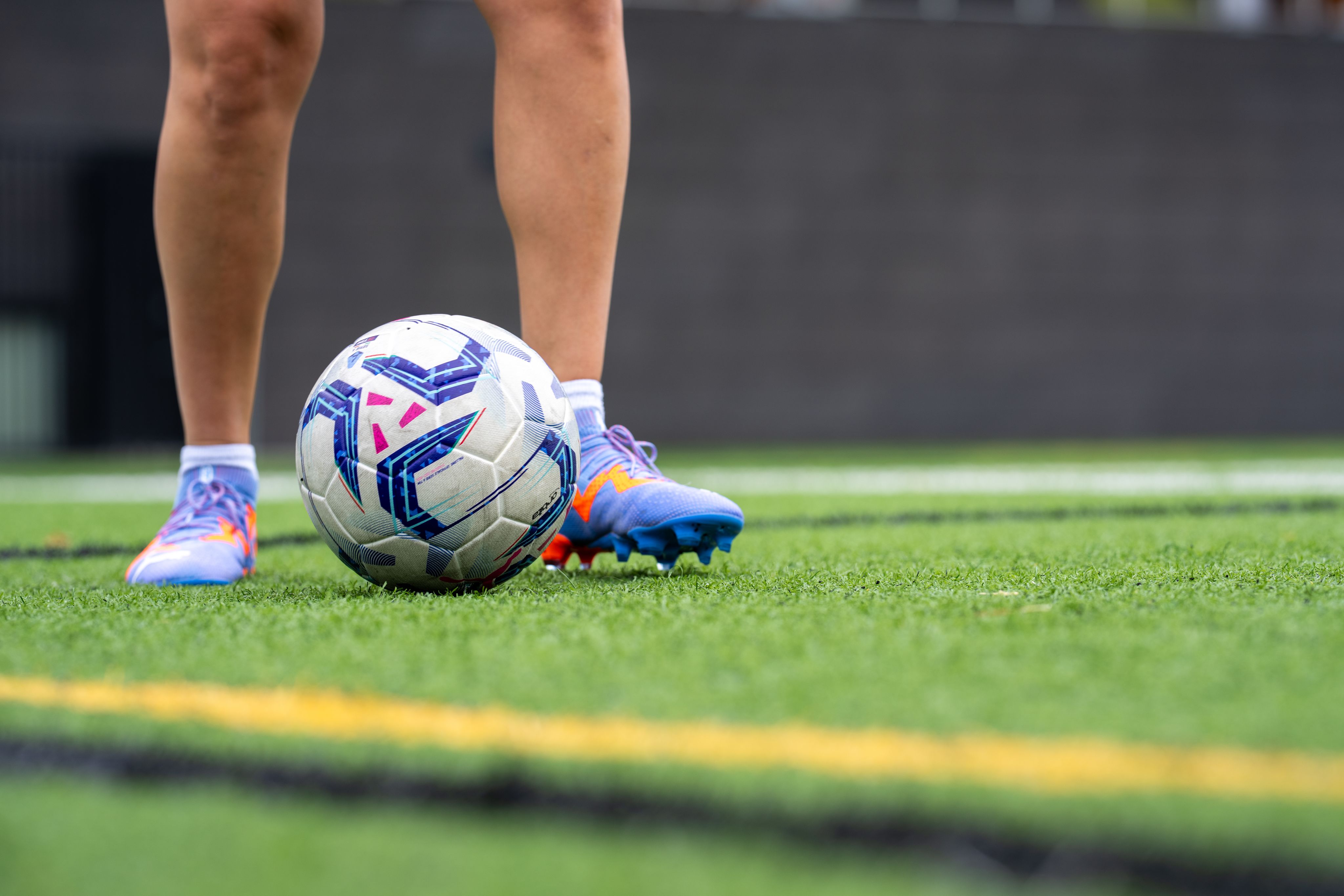 A soccer ball in play on a turf field