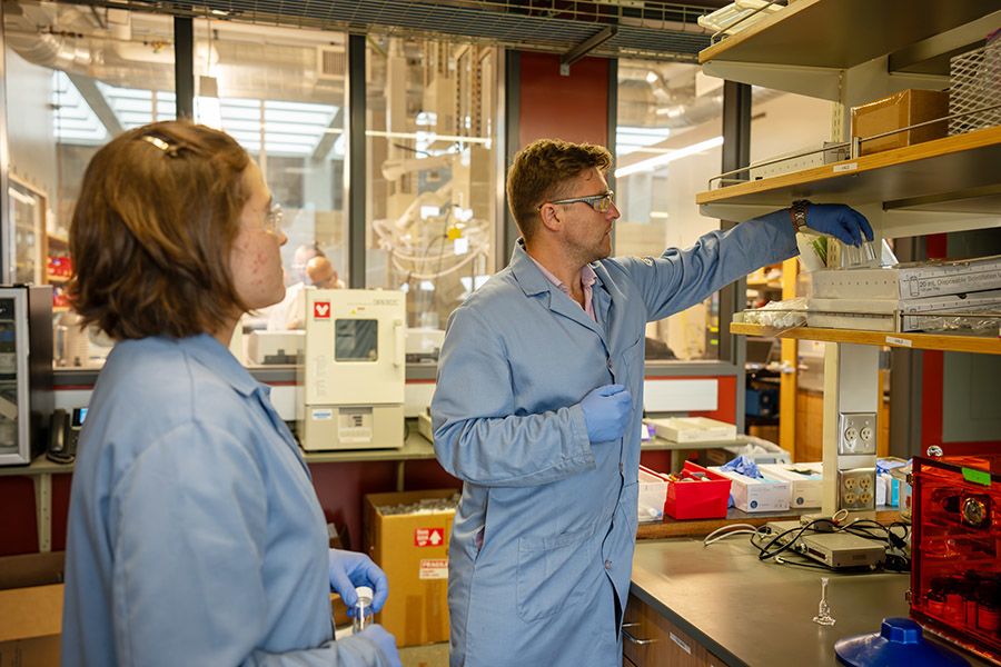 Two people in safety glasses and lab coats in a laboratory