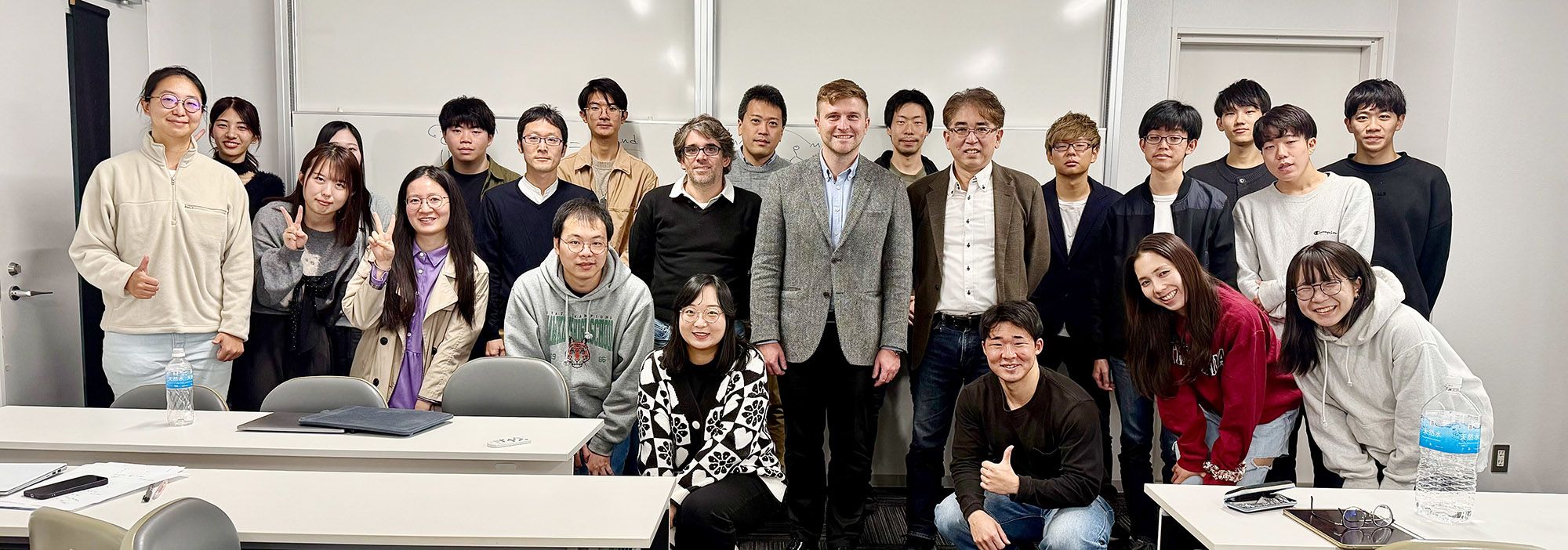 Group of 23 people in classroom looking at camera
