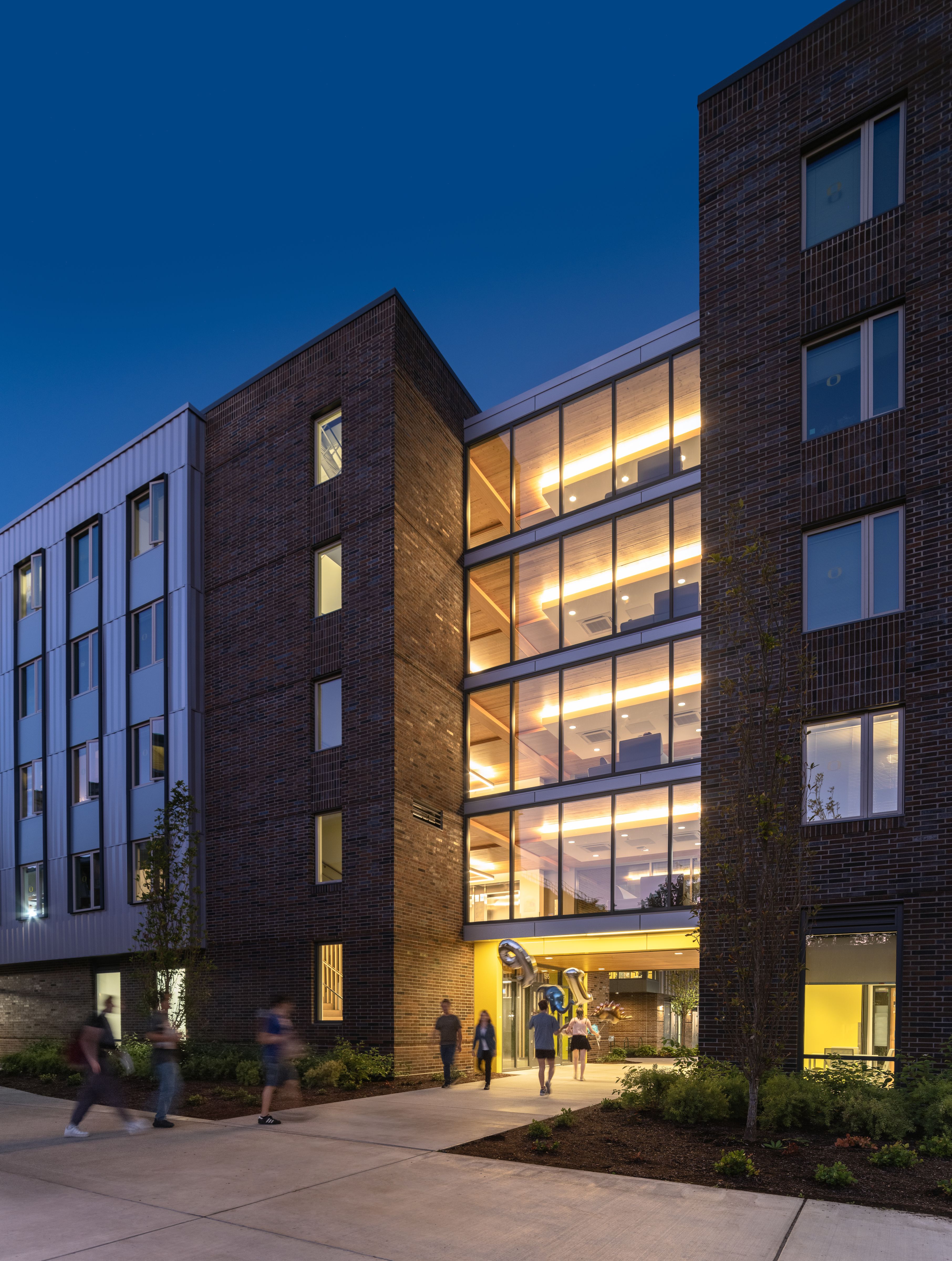 Exterior of Yasui Hall at night with students 